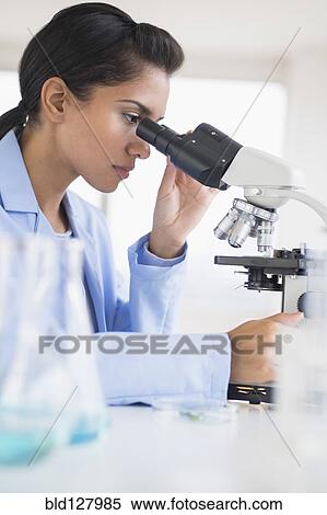 Stock Photography - Hispanic scientist using microscope in laboratory. Fotosearch