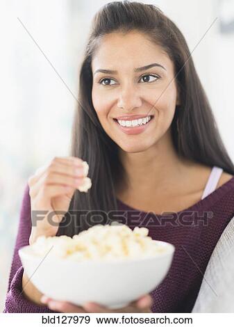 Stock Photo - Hispanic woman eating popcorn. Fotosearch