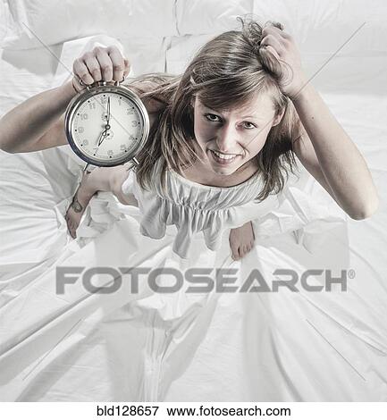 Hispanic woman holding alarm clock in bed View Large Photo Image Stock Photo - Hispanic woman holding alarm clock in bed. Fotosearch