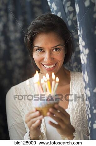 Stock Image - Hispanic woman holding birthday cupcake. Fotosearch