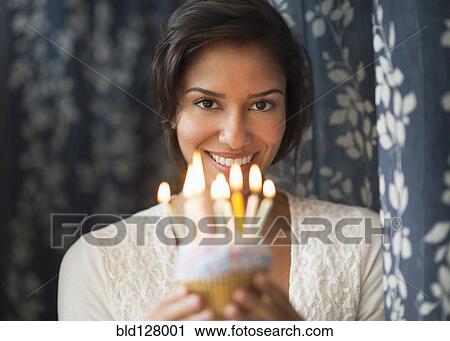Stock Image - Hispanic woman holding birthday cupcake. Fotosearch