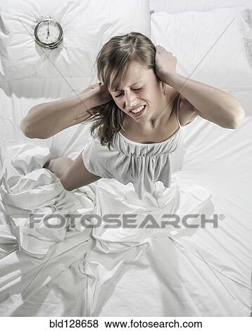 Stock Photo - Hispanic woman ignoring alarm clock in bed. Fotosearch