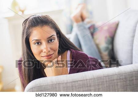 Stock Image - Hispanic woman laying on sofa. Fotosearch