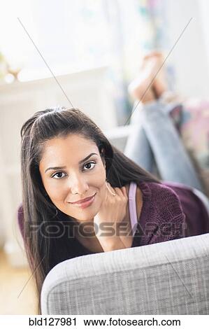 Stock Image - Hispanic woman laying on sofa. Fotosearch