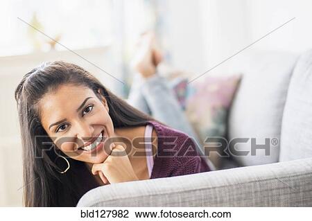 Stock Image - Hispanic woman laying on sofa. Fotosearch