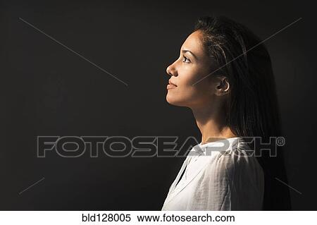 Stock Photography - Hispanic woman looking up into light. Fotosearch