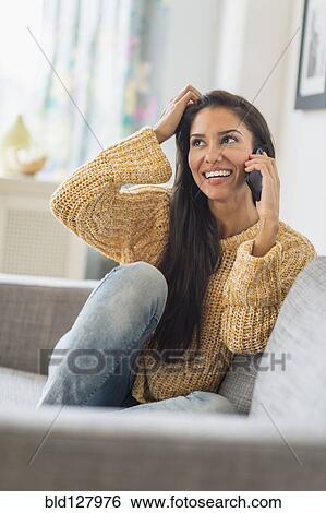 Hispanic woman talking on cell phone on sofa View Large Photo Image Stock Photograph - Hispanic woman talking on cell phone on sofa. Fotosearch