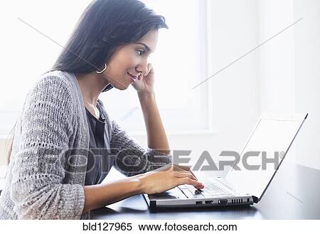 Hispanic woman using laptop on table View Large Photo Image Stock Photography - Hispanic woman using laptop on table. Fotosearch