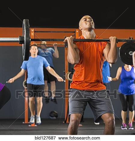 Stock Photo - Man lifting weights in gym. Fotosearch