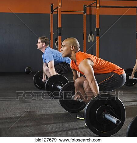 Stock Photo - Men lifting weights in gym. Fotosearch