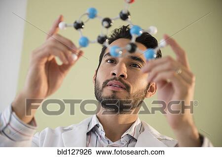 Stock Photograph - Mixed race businessman examining molecular model. Fotosearch