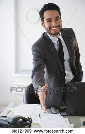 Stock Photo - Mixed race businessman offering handshake in office. Fotosearch