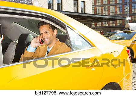Stock Photo - Mixed race businessman on cell phone in taxi. Fotosearch