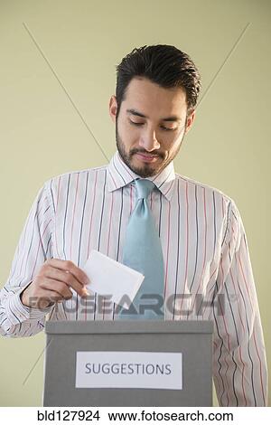 Picture - Mixed race businessman placing idea in suggestion box. Fotosearch