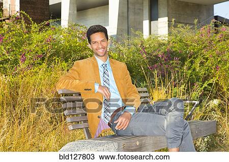 Mixed race businessman smiling on park bench View Large Photo Image Stock Image - Mixed race businessman smiling on park bench. Fotosearch