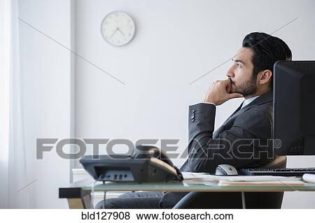 Stock Photo - Mixed race businessman thinking in office. Fotosearch