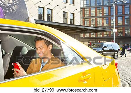 Stock Photo - Mixed race businessman using cell phone in taxi. Fotosearch