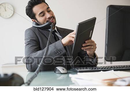 Mixed race businessman using digital tablet on telephone View Large Photo Image Picture - Mixed race businessman using digital tablet on telephone. Fotosearch