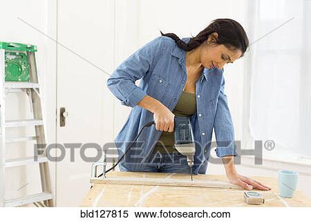 Stock Photography - Mixed race contractor working in shop. Fotosearch