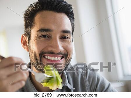 Stock Image - Mixed race man eating salad. Fotosearch