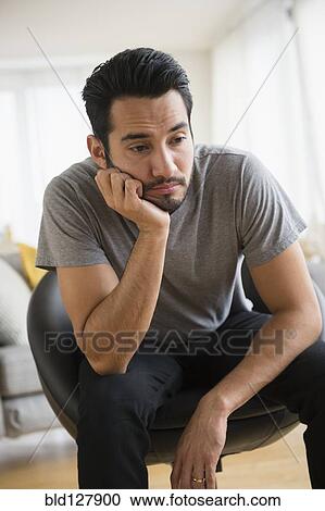 Stock Image - Mixed race man resting chin in hand. Fotosearch