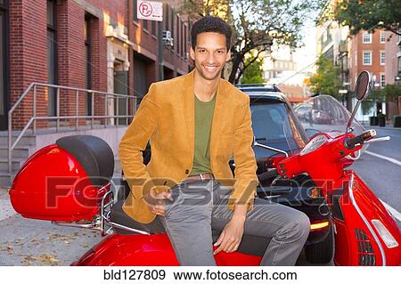 Mixed race man sitting on scooter on city street View Large Photo Image Stock Photo - Mixed race man sitting on scooter on city street. Fotosearch