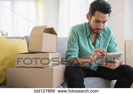 Stock Photo - Mixed race man using digital tablet and moving. Fotosearch
