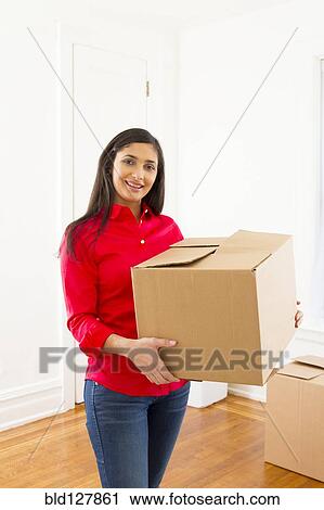 Stock Image - Mixed race woman carrying cardboard box. Fotosearch