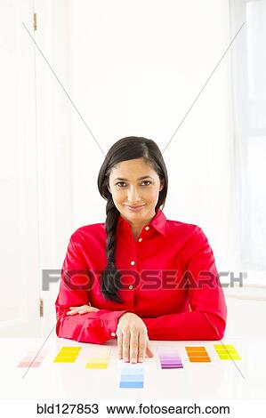 Stock Image - Mixed race woman examining paint swatches. Fotosearch
