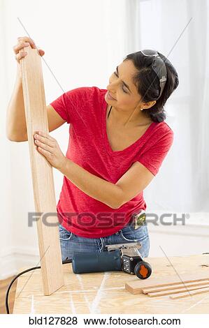 Mixed race woman examining plank of wood View Large Photo Image Stock Photo - Mixed race woman examining plank of wood. Fotosearch