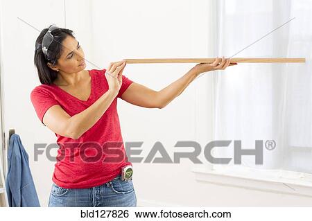 Stock Photograph - Mixed race woman examining plank of wood. Fotosearch