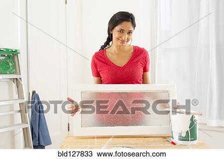 Stock Image - Mixed race woman making window pane. Fotosearch