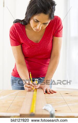 Mixed race woman measuring plank of wood View Large Photo Image Stock Image - Mixed race woman measuring plank of wood. Fotosearch