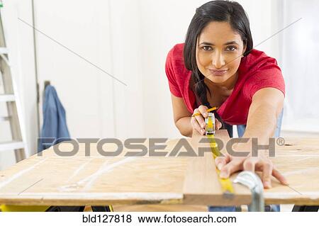 Mixed race woman measuring plank of wood View Large Photo Image Stock Photo - Mixed race woman measuring plank of wood. Fotosearch