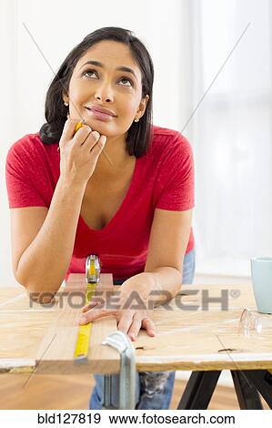 Stock Photo - Mixed race woman measuring plank of wood. Fotosearch