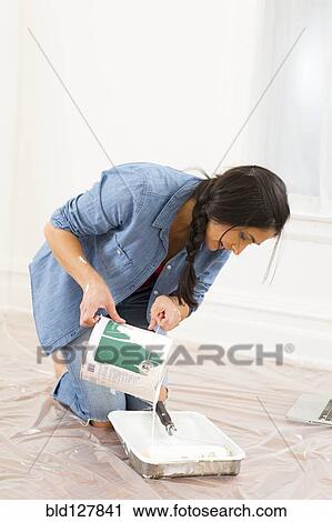 Stock Image - Mixed race woman painting room. Fotosearch