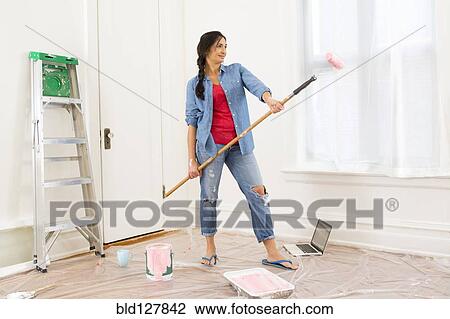 Mixed race woman painting room View Large Photo Image Stock Image - Mixed race woman painting room. Fotosearch