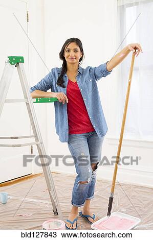 Stock Image - Mixed race woman painting room. Fotosearch