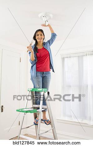 Stock Photography - Mixed race woman painting room. Fotosearch