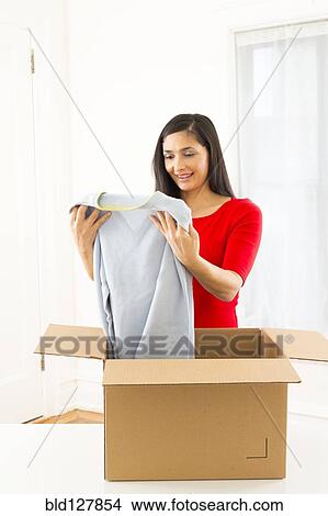 Picture - Mixed race woman unpacking cardboard box. Fotosearch