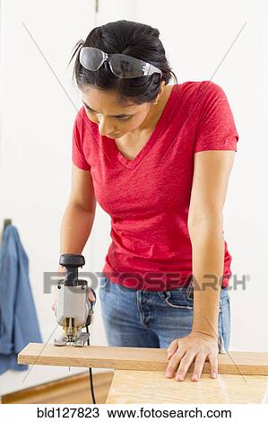 Stock Image - Mixed race woman using jigsaw. Fotosearch