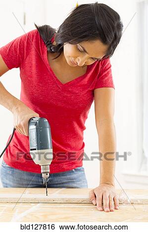 Mixed race woman using power drill View Large Photo Image Stock Photograph - Mixed race woman using power drill. Fotosearch