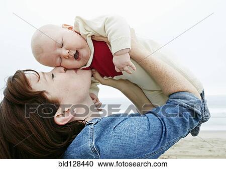 Stock Image - Mother kissing baby on beach. Fotosearch
