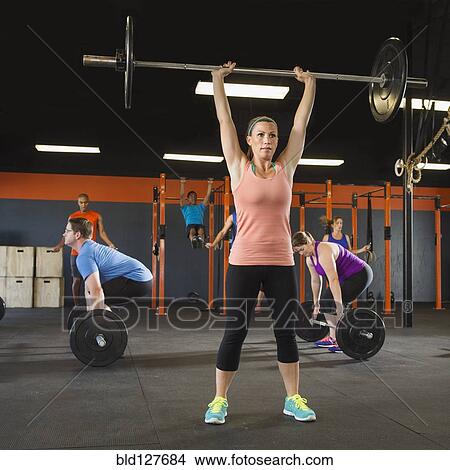 Picture - People lifting weights in gym. Fotosearch