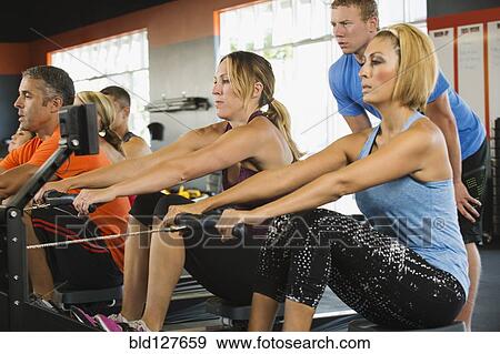 Stock Photo - People using rowing machines in gym. Fotosearch