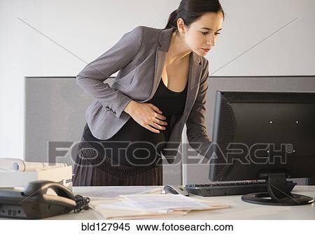 Stock Photography - Pregnant Caucasian businesswoman working in office. Fotosearch