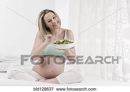 Pregnant Caucasian woman eating salad View Large Photo Image Stock Photo - Pregnant Caucasian woman eating salad. Fotosearch