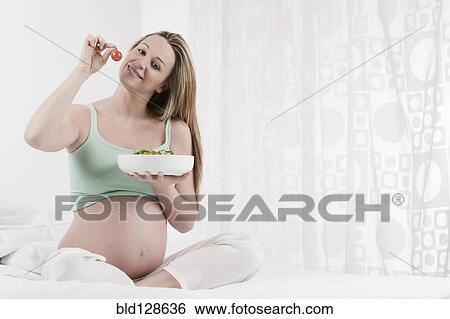 Stock Photograph - Pregnant Caucasian woman eating salad. Fotosearch