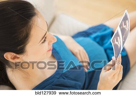 Stock Photo - Pregnant Caucasian woman examining ultrasounds. Fotosearch