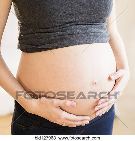 Stock Image - Pregnant Caucasian woman holding belly. Fotosearch